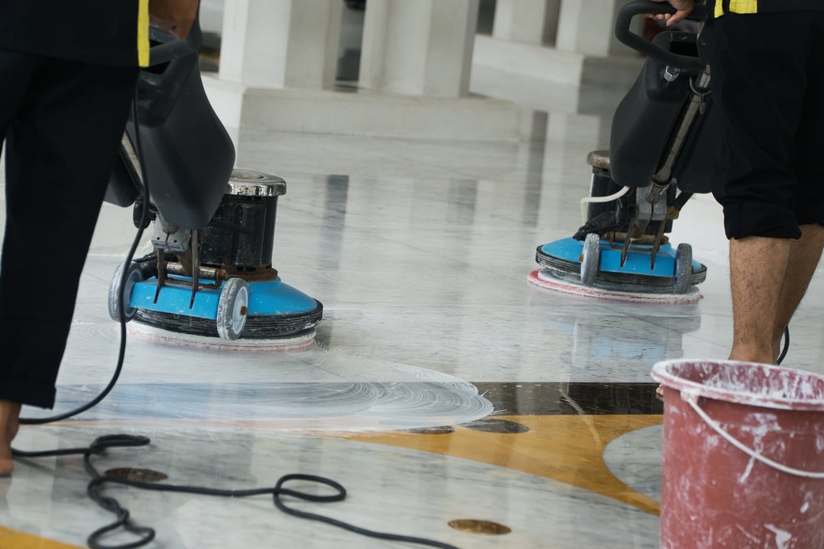Professionals using industrial polishing equipment on marble — specialist restoration required